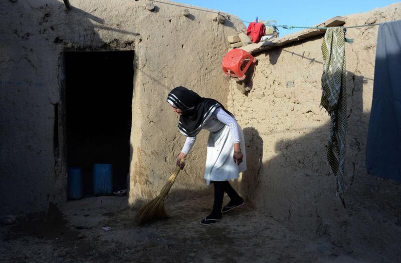 Aziza Rahimzada cleans the courtyard outside her temporary home at a refugee camp in Kabul.