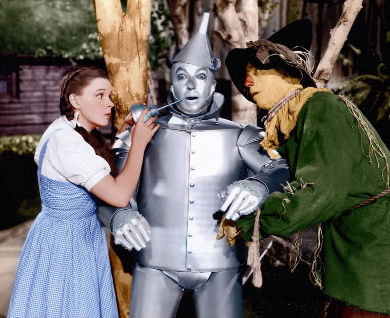 Judy Garland as Dorothy Gale gives Jack Haley's Tin Man a little oil from the can, as the Scarecrow, played by Ray Bolger, looks on. Shutterstock
