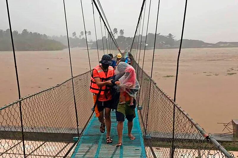 Rescuers help residents cross a bridge to safety in Tubay town, Agusan del Norte, southern Philippines. Photo: AP Photo