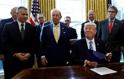 FILE PHOTO: U.S. President Donald Trump smiles after announcing a permit for TransCanada Corp's Keystone XL oil pipeline while TransCanada Chief Executive Officer Russell Girling (L), U.S. Commerce Secretary Wilbur Ross (C) and Energy Secretary Rick Perry (R) stand beside him in the Oval Office of the White House in Washington, U.S., March 24, 2017. REUTERS/Kevin Lamarque/File Photo