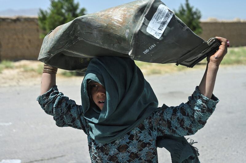 A girl carries a metal box she collected from a junkyard near the Bagram Air Base. AFP