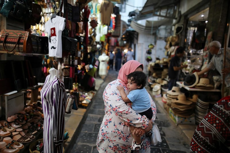 Tourists walk past traditional souvenirs displayed for sale in the old city of Tunis, Tunisia. Reuters