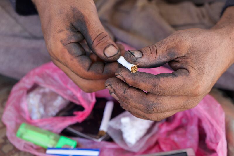 A Palestinian worker rolls a cigarette during a break from processing plastic.