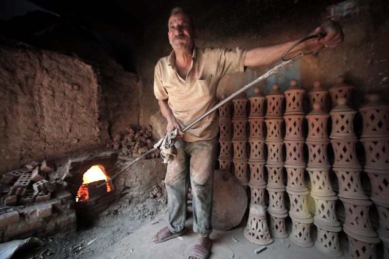 An Egyptian worker puts the wood inside a traditional oven at a pottery workshop.