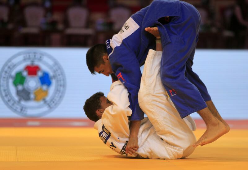 Denislar Ivanov, in blue from Bulgaria, fights with Ahmed Abelrahman from Egypt on the opening day of the International Judo Federation (IJF) Junior World Championships, which started at the Ipic Arena at the Zayed Sports City in Abu Dhabi on Friday. Ravindranath K / The National