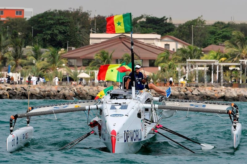 Patrick Bol, Dutch skipper of the Row4ocean rowing trimaran, holds a Senegalese flag as the Row4Ocean crew depart West Africa on their transatlantic challenge. AFP