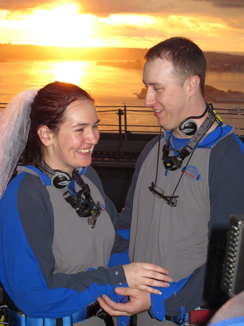 A handout photo taken and released by BridgeClimb on February 14, 2012 shows Sydneysiders Katrina Aplitt (L) and Cameron McCloughan (R) taking their wedding vows at dawn on Valentine's Day on top of the Sydney Harbour Bridge.  More than 2.75 million people have climbed the bridge to date, with over 4000 couples becoming engaged and 20 weddings taking place on the summit of the iron arch 134 metres above Sydney Harbour.       --- EDITORS NOTE --- RESTRICTED TO EDITORIAL USE MANDATORY CREDIT  NO MARKETING NO ADVERTISING CAMPAIGNS - DISTRIBUTED AS A SERVICE TO CLIENTS   AFP PHOTO / HO / BridgeClimb
 *** Local Caption ***  863776-01-08.jpg