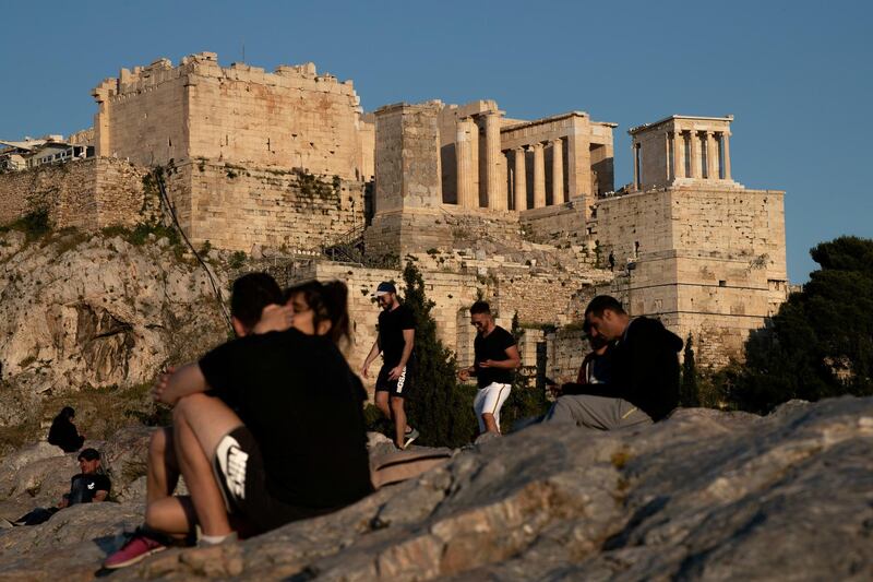 People visit the Areios Pagos hill with the Acropolis' Propylaea seen in the background, following the coronavirus disease (COVID-19) outbreak, in Athens, Greece,  Reuters