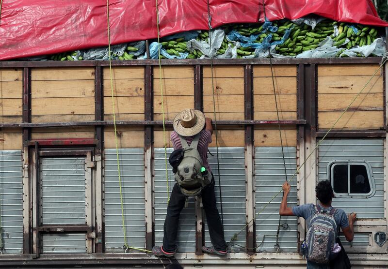 Migrants climb onboard a truck to hitchhike along the highway to Sayula de Aleman from Donaji, Mexico. Reuters