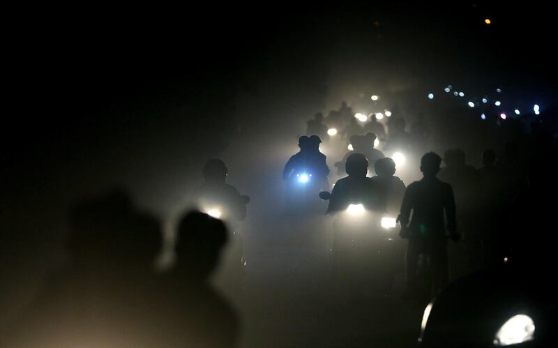 Indian motorists ride past a thick blanket of smog and dust on the outskirts of New Delhi, India. Altaf Qadri / AP Photo