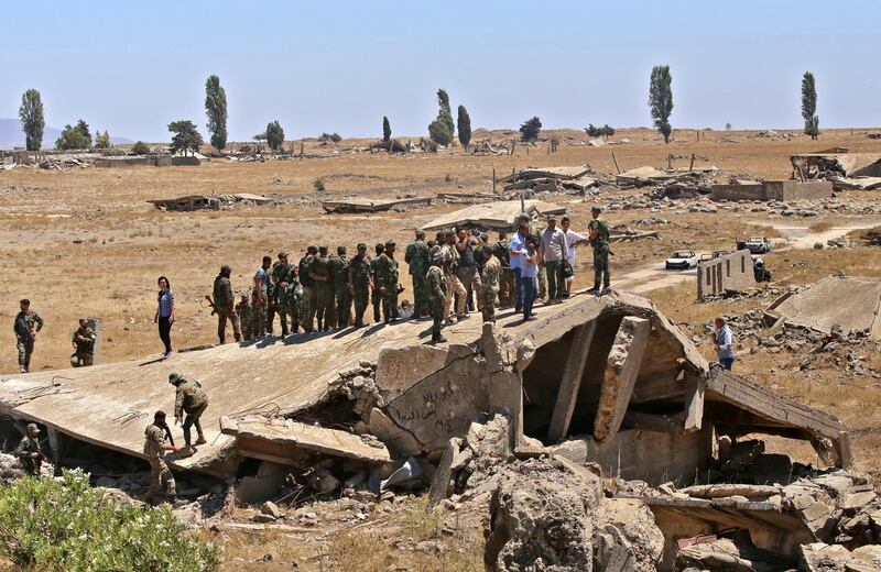 Syrian soldiers stand atop a destroyed building in the town of Quneitra in the Syrian Golan Heights on July 27, 2018. - The town was almost completely destroyed by departing Israeli soldiers in 1974 after seven years of occupation. (Photo by Youssef KARWASHAN / AFP)