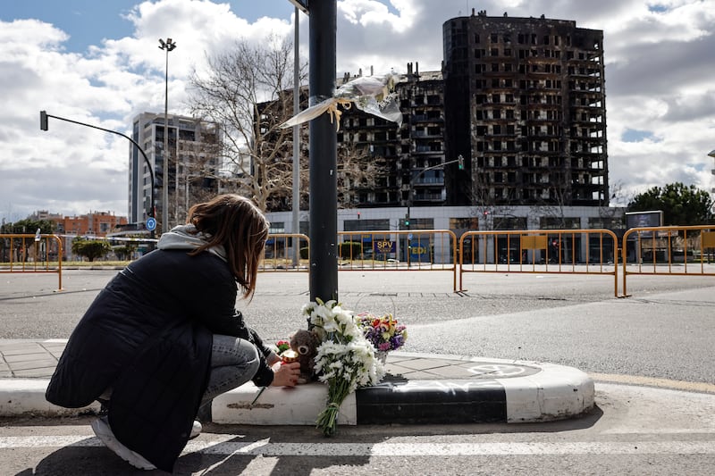 A woman lays flowers near the apartment block in Valencia, Spain, where at least 10 people died in a fire. EPA