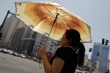 A woman shields herself from Abu Dhabi's summer sun. Ryan Carter / The National  