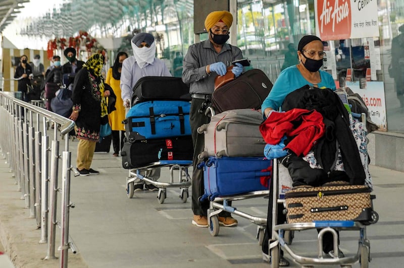 Canadian nationals queue to check-in before boarding a special flight for New Delhi to eventually reach Canada during a government-imposed nationwide lockdown as a preventive measure against the COVID-19 coronavirus, at Sri Guru Ram Dass Jee International Airport in Amritsar on April 9, 2020. / AFP / NARINDER NANU

