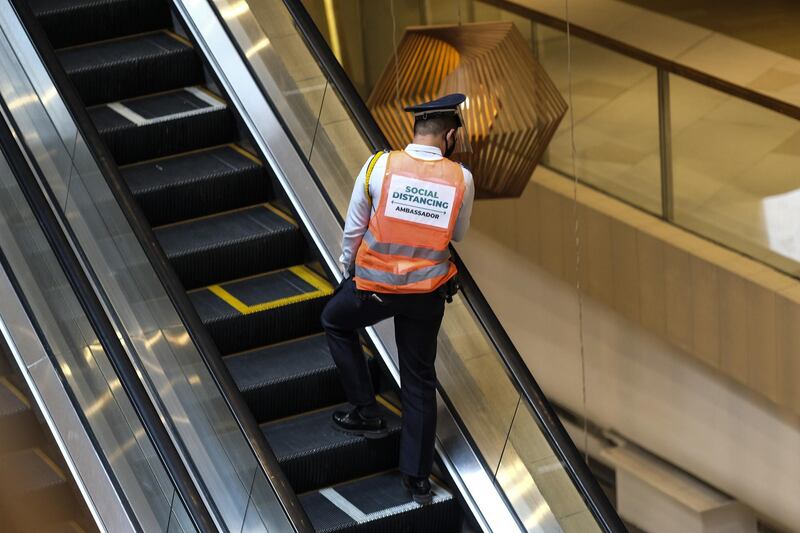 A security guard wearing a vest reading "Social Distancing Ambassador" rides on an escalator inside Megaworld Corp.'s Uptown Mall in Bonifacio Global City in Metro Manila, the Philippines. Bloomberg