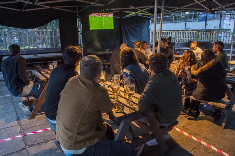 People drink at tables outside at a bar while watching live sports in Manchester, U.K., on Saturday, Sept. 12, 2020. From Sept. 14 police will have new powers to disperse and fine any group larger than six people meeting indoors or outdoors. Photographer: Anthony Devlin/Bloomberg