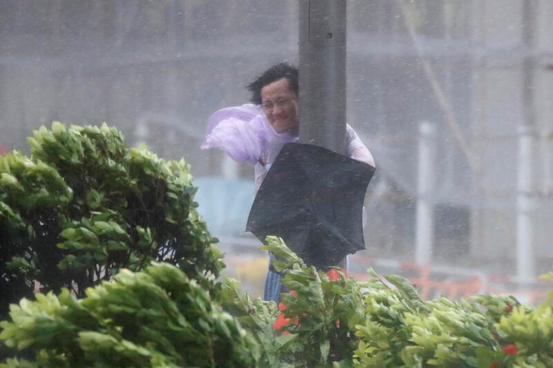 A man holds onto a lamp post against strong wind as Typhoon Hato hits Hong Kong. Tyrone Siu / Reuters.