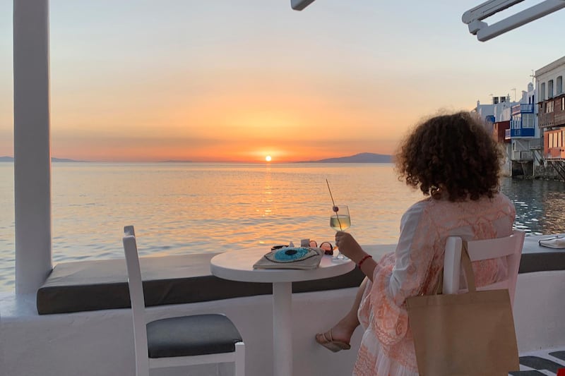 A visitor watches the sunset in an area known as Little Venice in the main town of the island of Mykonos, Greece. AP photo