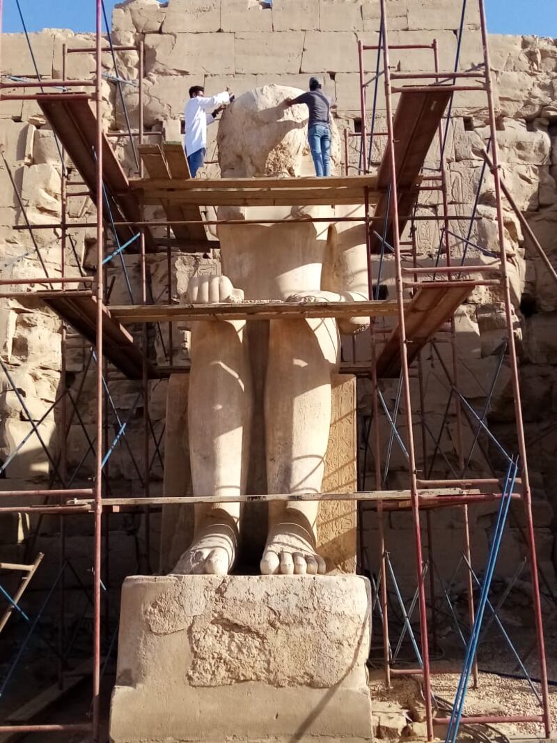 Egyptian restoration workers on a scaffolding during a project to repair the severely damaged statue of Thutmose II located in Luxor's Karnak Temple.