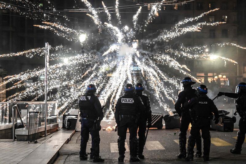 Police stand in front of fireworks fired by protesters during a demonstration against the French government's pensions reform. AFP

