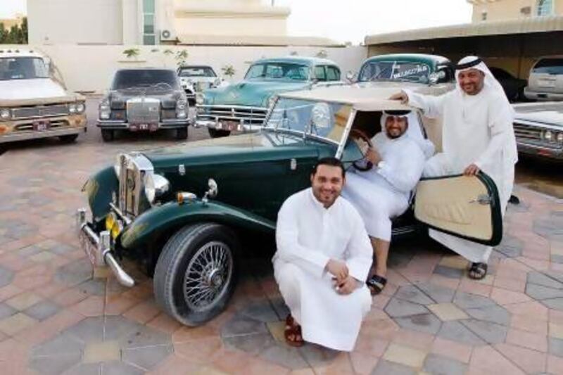 From left, Jaber, Faisal and Jasim Al Mubarak with a small selection of the classics they have restored over the years. Sarah Dea / The National