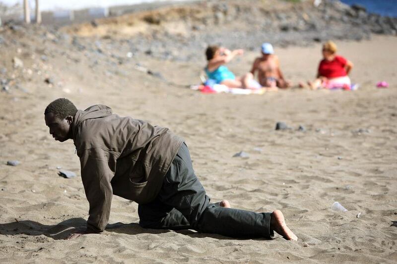 A would-be immigrant crawls on the beach after his arrival on a makeshift boat on the Gran Tarajal beach in Spain’s Canary Island of Fuerteventura, on May 5, 2006. Juan Medina / Reuters