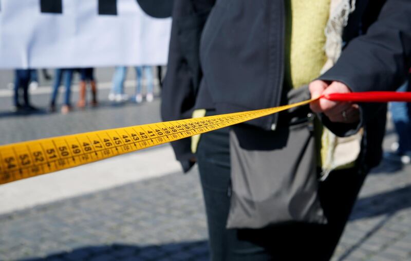 A person holds a measuring tape during the protest against war in Syria, keeping one metre distance at St. Peter's Square. Reuters