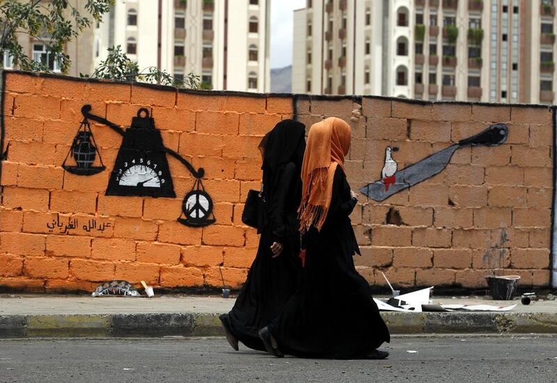 Two Yemeni women pass a wall full of graffiti in support of peace in the war-affected country, at a wall along a street in Sana'a, 30 April 2016. Yahya Arhab / EPA  