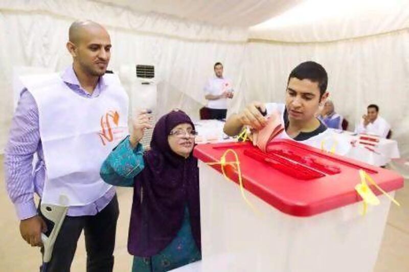 The Dubai polling station manager Khalid Hijazi watches as Najwa Mohamed, 76, places her vote in the ballot box with the help of Ezeddean Hassan yesterday.