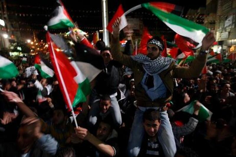 Palestinians wave Palestinian flags as they watch a large screen showing the U.N. General Assembly votes on a resolution to upgrade the status of the Palestinian Authority to a nonmember observer state, In the west bank city of Ramallah, Thursday, Nov. 29, 2012.  The U.N. General Assembly has voted by a more than two-thirds majority to recognize the state of Palestine. The resolution upgrading the Palestinians' status to a nonmember observer state at the United Nations was approved by the 193-member world body late Thursday by a vote of 138-9 with 41 abstentions. (AP Photo/Majdi Mohammed)