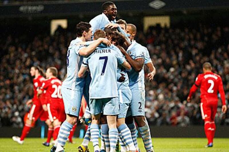 City's Yaya Toure, obscured, celebrates with teammates including his brother Kolo Toure, top, after scoring against Liverpool.