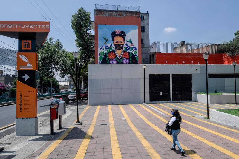 A woman walks past a mural called 'Frida in pandemic times' painted by the urban artist Julio Aferra. AFP