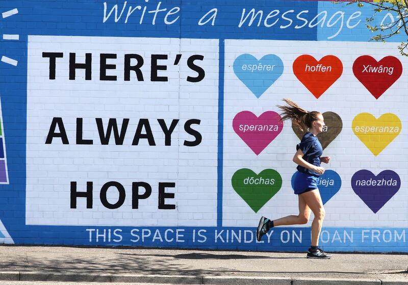 A woman runs past a mental health mural on the Falls road in west Belfast. (Photo by Peter Morrison/PA Images via Getty Images)