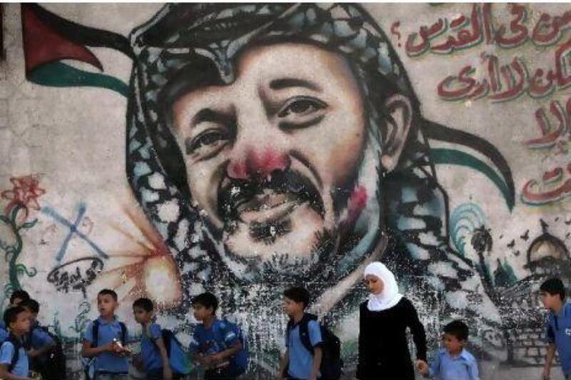 Palestinian schoolchildren stand with a woman in front of a painting of the late Palestinian leader, Yasser Arafat, in central Gaza yesterday. Mahmud Hams /AFP