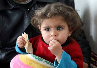 Raghad Ismail, a Syrian toddler who was rescued from rubble of a collapsed building after the earthquake, sits on her uncle's lap at his home in rebel-held Azaz, Syria. Reuters