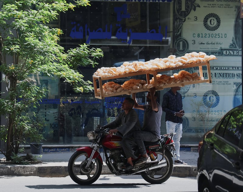 Egyptian street sellers travel past a currency exchange point in Cairo. Reuters