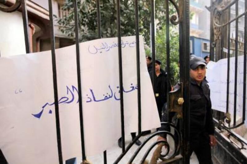 An Egyptian policeman on strike stands at the gate of the Qasr el-Nile police station, in front of a banner that reads: "Closed for the end of our patience," during a protest in Cairo this month. Amr Nabil / AP Photo