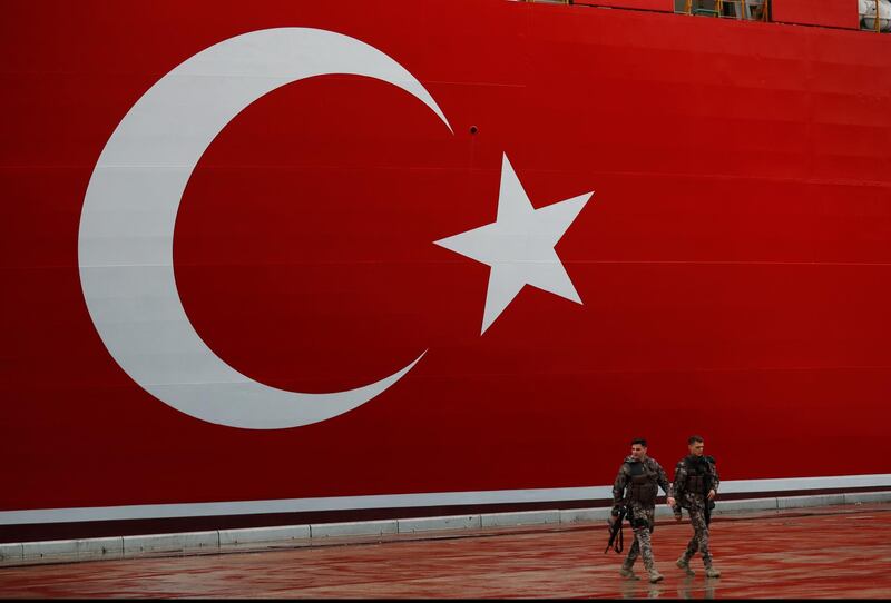 Turkish police officers patrol the dock, backdropped by the drilling ship 'Yavuz' scheduled to be dispatched to the Mediterranean, at the port of Dilovasi, outside Istanbul. AP