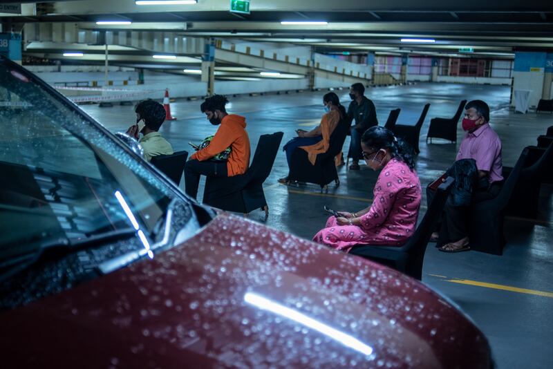 People who were inoculated sit under observation during a drive in facility for Covid-19 vaccination at a car parking area of a shopping mall in Kochi, Kerala state, India.  AP