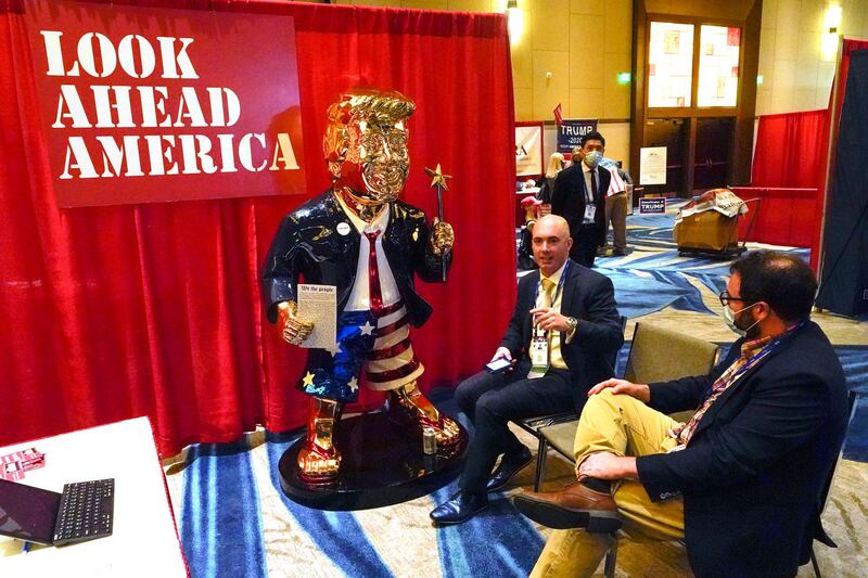 Conservative figure Matt Braynard, left, talks to conference attendees next to the golden statue of former president Donald Trump, at the Conservative Political Action Conference. AP Photo