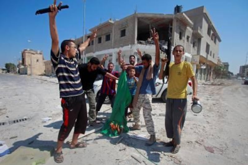 Libyan rebel fighters burn a Gaddafi government flag in the main square after seizing control of the center of the strategic coastal city of Zawiyah, August 20, 2011.   REUTERS/Bob Strong  (LIBYA - Tags: CIVIL UNREST POLITICS) *** Local Caption ***  RCS01_LIBYA-_0820_11.JPG