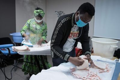 Undocumented immigrants Cameroonian Florence irons home made protective facemasks for The Salvation Army (Armee du Salut) charitable organisation, in Paris, on April 6, 2020, on the twenty-first day of a strict lockdown in France to stop the spread of COVID-19 (novel coronavirus).  / AFP / JOEL SAGET
