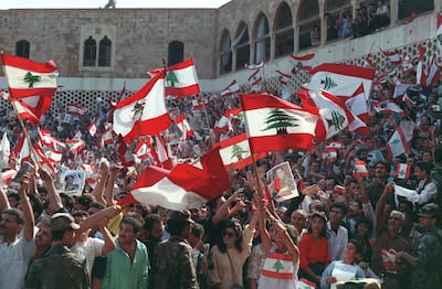 Christian Lebanese people wave national flags and portraits of General Aoun while they stage a protest 04 November 1989 in front of Baabda presidential palace in East Beirut against agreement reached in October by deputies and the Arab League Committee in Taif.  After a month of intense discussion, in October 1989, the deputies informally agreed on a charter of national reconciliation, also known as Taif agreement. General Aoun, claiming powers as interim Prime Minister, issued a decree in early November dissolving the parliament and did not accept the ratification of the Taif agreement. The Lebanese civil war broken out in April 1975. AFP PHOTO JOSEPH BARRAK (Photo by JOSEPH BARRAK / AFP)