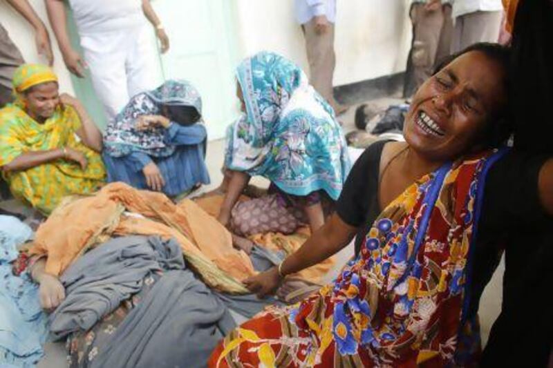 People mourn with the bodies of relatives, who died inside the rubble of the collapsed Rana Plaza building, in Savar outside of Dhakar.