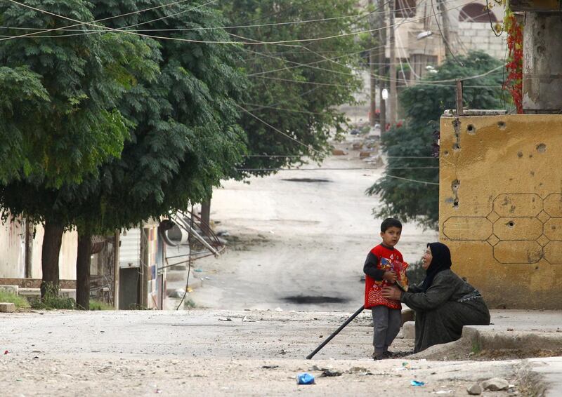 An elderly woman and a child are seen along a deserted street in the town of Ras Al Ain. Reuters