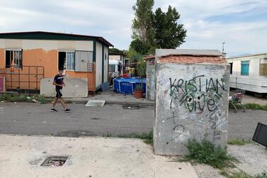 'A resident of the Salone Camp for Italy's Roma ethnic minority passes a static caravan; the camp, which is home to 400  inhabitants, lies 15km from the centre of Rome. Callum Paton / The National