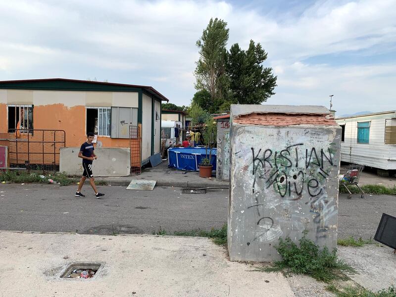 'A resident of the Salone Camp for Italy's Roma ethnic minority passes a static caravan; the camp, which is home to 400  inhabitants, lies 15km from the centre of Rome. Callum Paton / The National