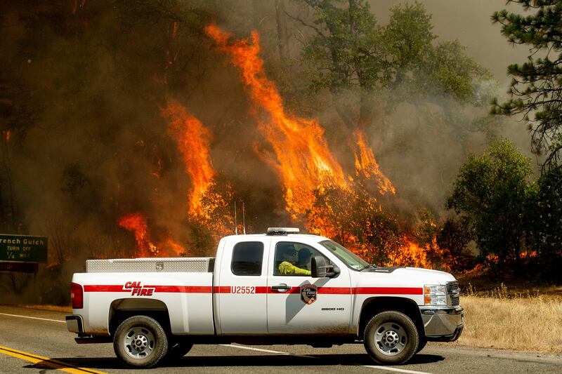 Flames from the Carr Fire lick above a Cal Fire truck in Whiskeytown, California. The flames moved so fast that firefighters working in oven-like temperatures and bone-dry conditions had to drop efforts to battle the blaze at one point to help people escape. AP Photo / Noah Berger