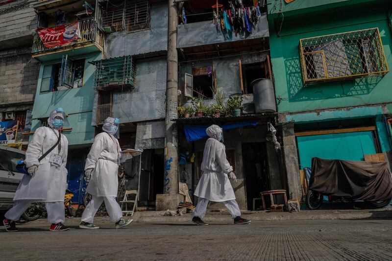 Health care workers (L-R) Vanessa Morales, Richell Arsenio and Fe Bacunawa prepare to enter an alley in Manila, Philippines. They are part of a group of four volunteer health workers who were nicknamed 'Astronauts' by residents of Village 775, Zone 84 in Manila as they resemble such when donning their protective equipment. The healthcare volunteers conduct home visits twice a day to people infected or suspected to be infected with the novel SARS-CoV-2 coronavirus that causes the COVID-19 disease in one of the densely populated villages in Manila.  EPA