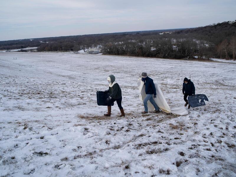 A group climbs a steep, snow-covered hill next to Lake Waco dam in Texas. AFP